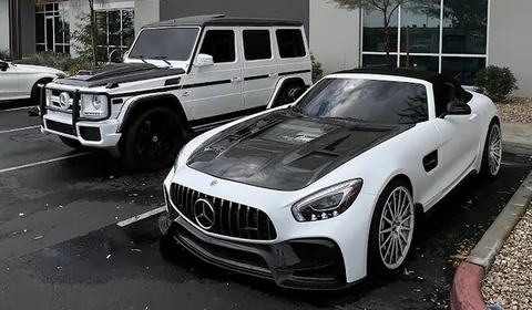 White Mercedes AMG GT R with a carbon fibre hood parked beside a white G-Class