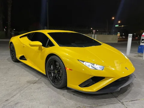 Yellow Lamborghini Huracan with black wheels, front three quarter view at night